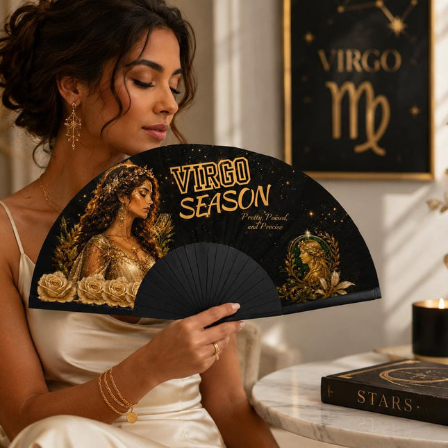 May include: A black folding hand fan featuring a gold-toned illustration of a woman, white roses, and the text "VIRGO SEASON" along with the smaller script "Pretty, Poised, and Precise" set against a dark, starry background with gold accents.